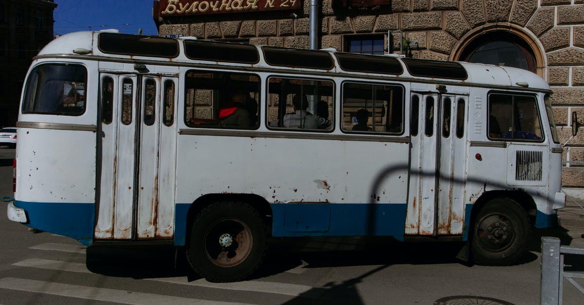 Why do airlines seat people the way they do? - Old fashioned rusty bus with people driving on intersection at corner of city street