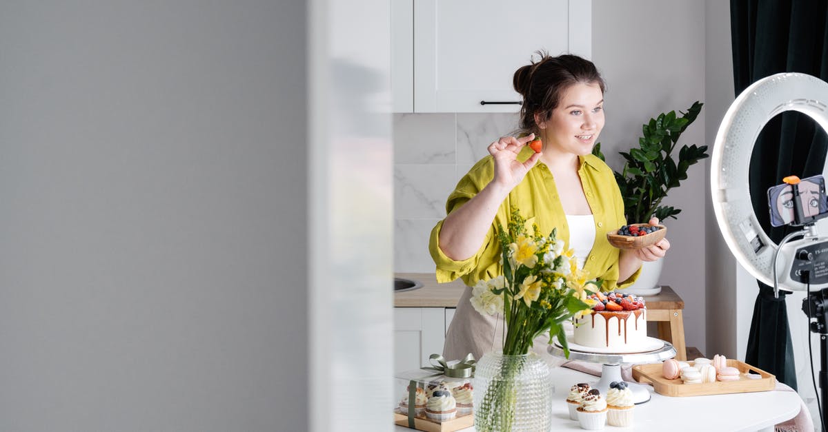 Why do airlines (typically?) require customers to phone for special meals, and not provide this option online? - Delighted young female influencer in casual clothes smiling and demonstrating fresh berries while decorating appetizing cake during recording vlog on smartphone in kitchen