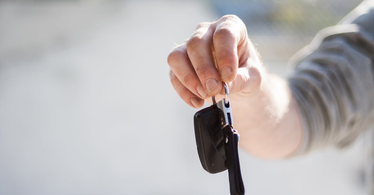 Why do rental car companies hand you two keys wired together? - Person in Grey Shirt Handing Keys