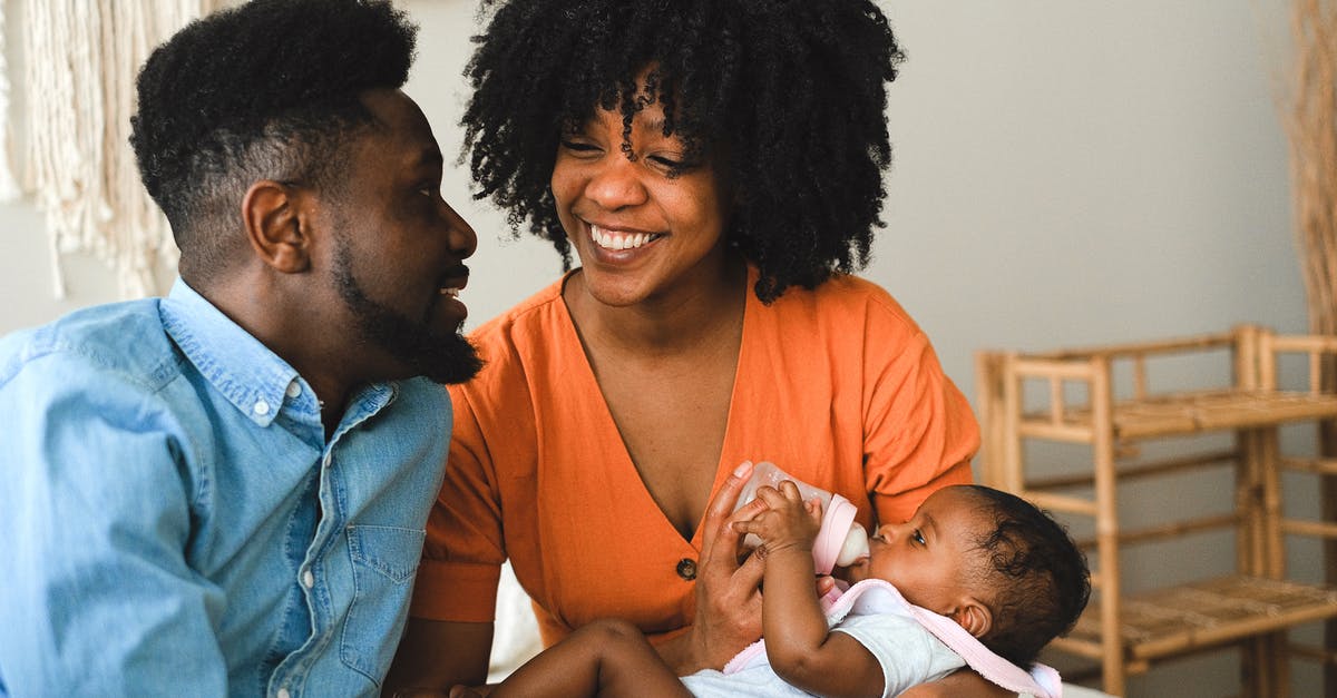 Why do some groups of tourists include someone carrying a banner? - Happy Couple Sitting on Bed Carrying a Baby