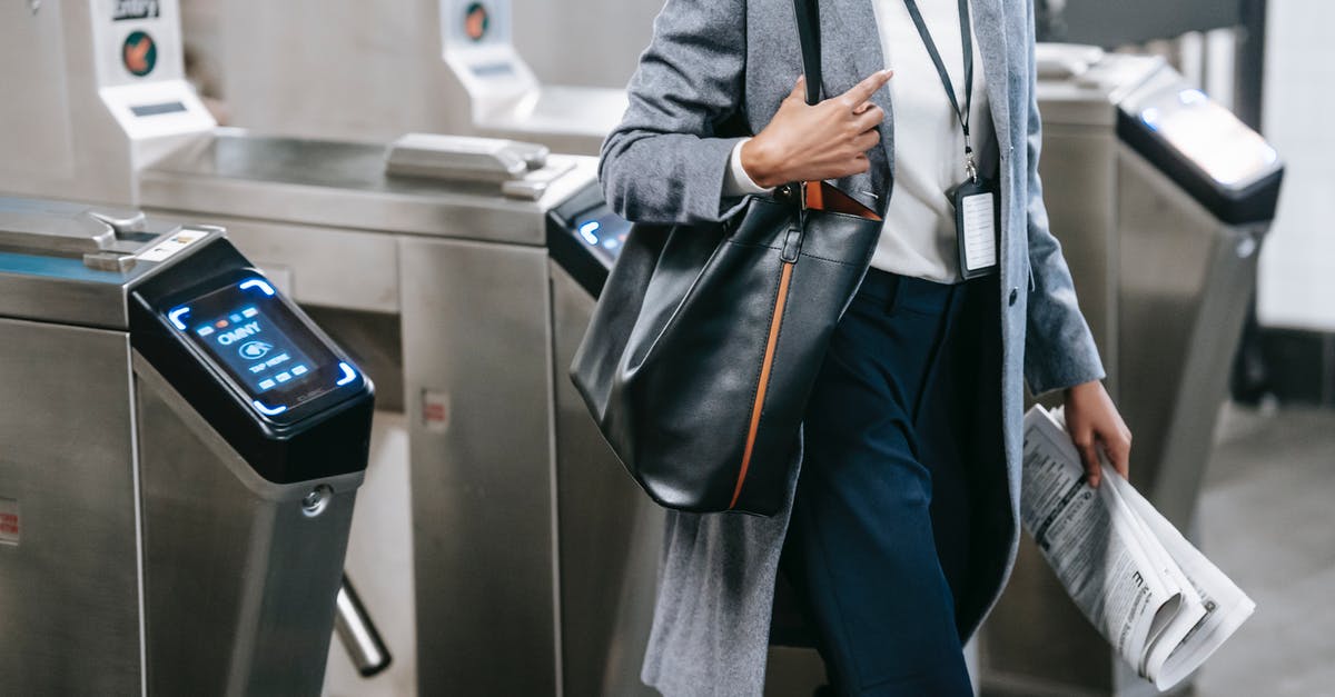 Why do some Smart Gate passports need to be stamped? - Crop anonymous African American female in formal clothes with newspaper passing through turnstile gates in modern underground station