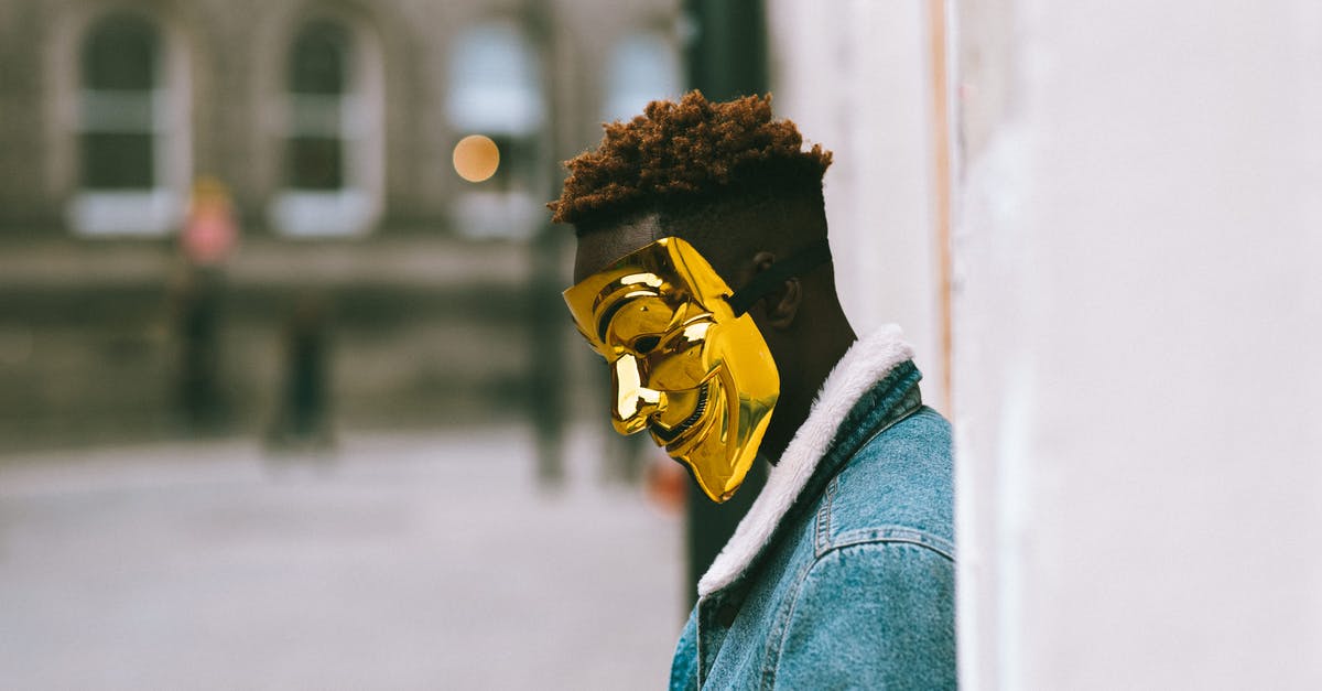 Why does Rotterdam not want me to lean against buildings? - Side view of thoughtful African American activist wearing golden Anonymous mask as symbol of protest against current state policy standing near building on city street in daytime