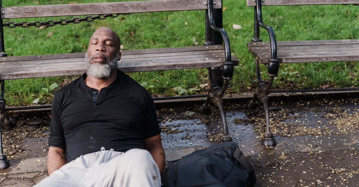 Why is homelessness not an issue in Tokyo? [closed] - Man in Black Polo Shirt Sitting on Brown Wooden Bench