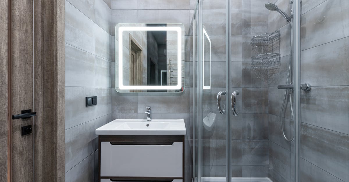 Why is the bathroom's light switch outside the room in some countries? - Contemporary washbasin under mirror against shower room with glass walls and tiles at home