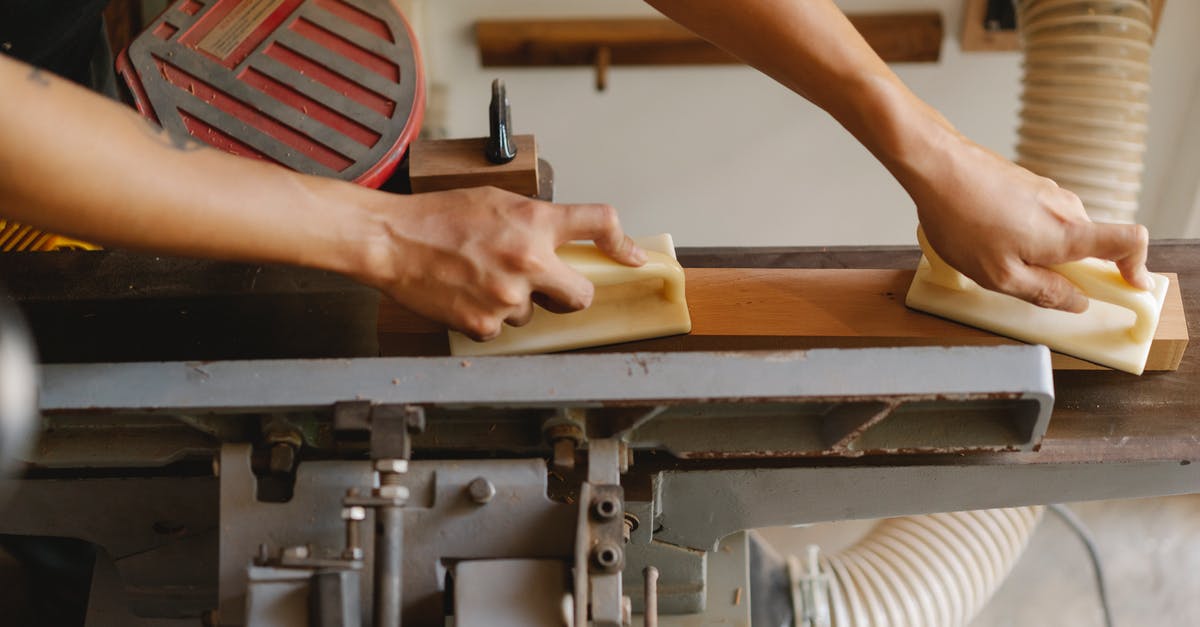 Why is the departures level always above the arrivals level? - From above of crop anonymous woodworker leveling timber on professional equipment using manual instruments in workroom in daylight