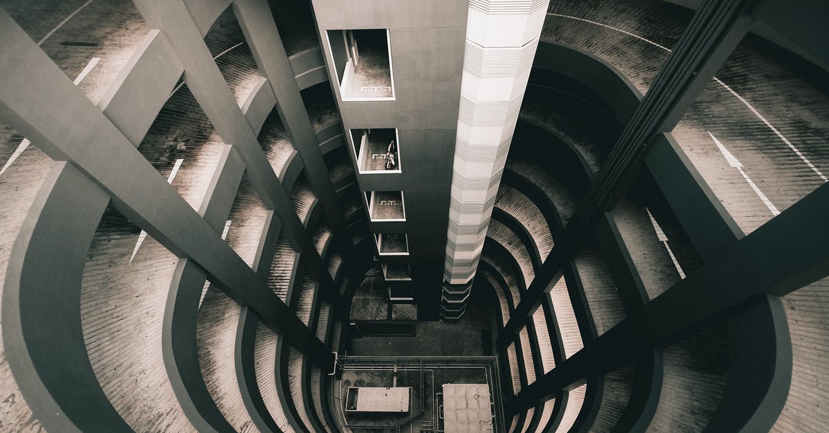 Why is the departures level always above the arrivals level? - Futuristic concrete building of multilevel parking