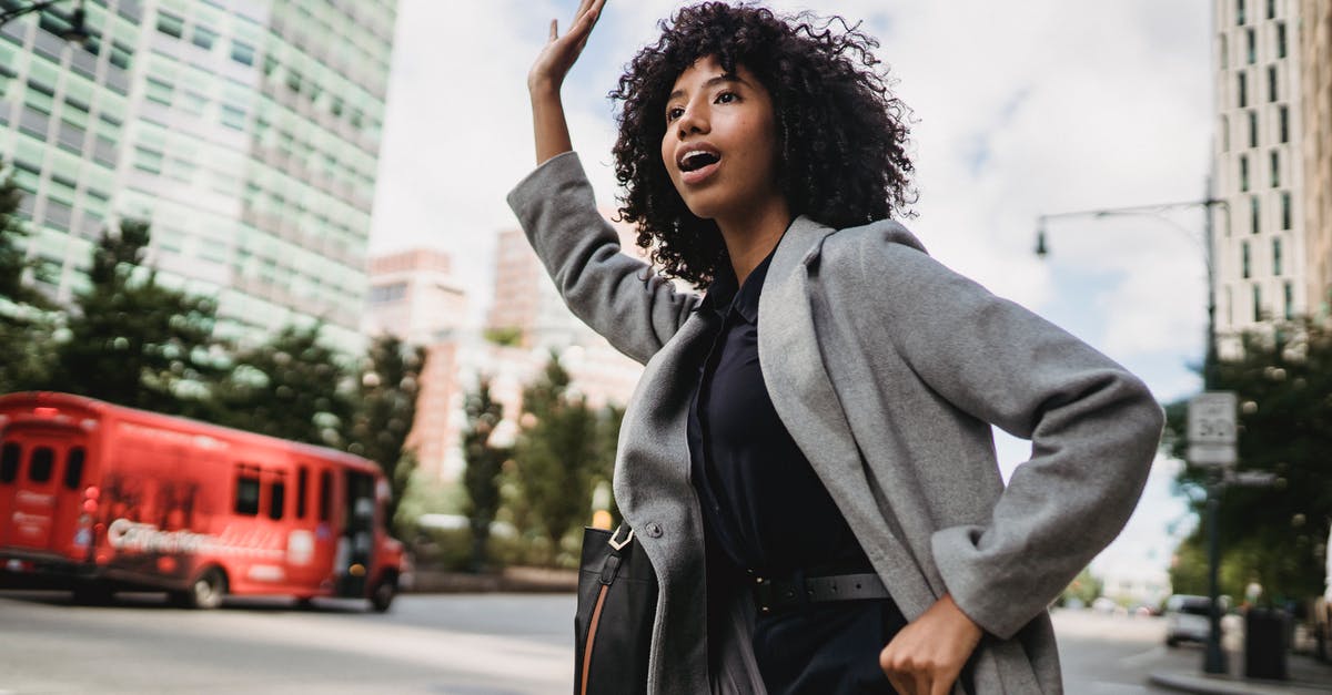 Why won't my bus show up on greyhound's live tracker website? - Young African American female with Afro hairstyle waving hand on city road while looking away