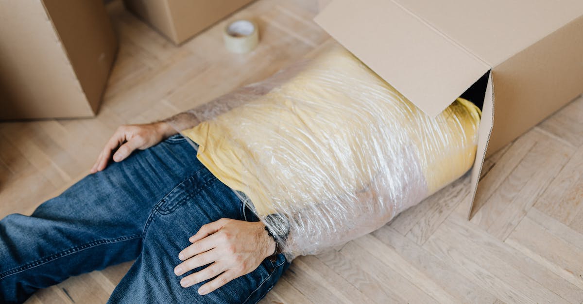 Why would you wrap your luggage in plastic? - Man tied up using tape with head in carton box