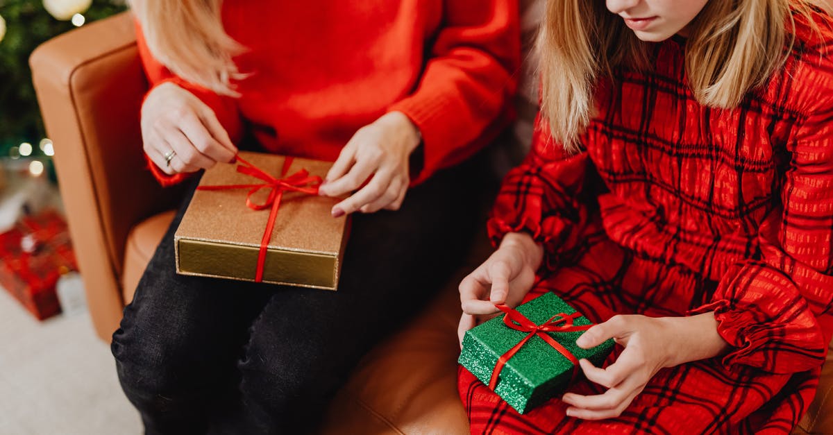 Will businesses be open on Christmas in Mexicali? - Woman in Red Long Sleeve Shirt Holding Black and Red Gift Box