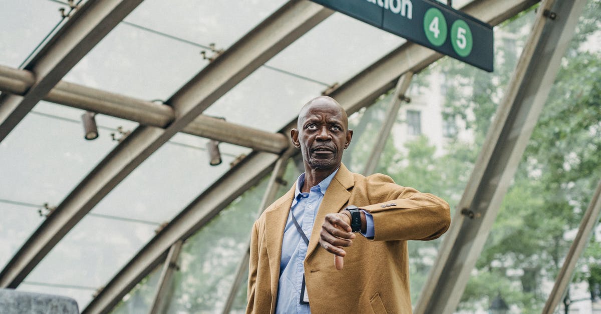 Will I be able to retrieve my checked bags on a 15 hour layover in Narita? - Pondering black businessman checking time on wristwatch near subway station