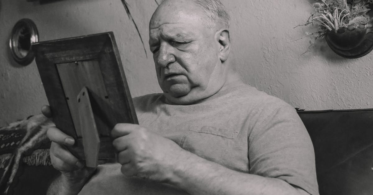 Will I have problems re-entering England? - A Grayscale Photo of an Elderly Man Holding a Wooden Frame