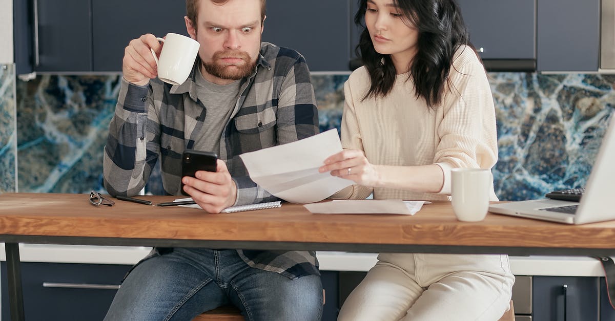 Will I have problems re-entering England? - A Man Looking at the Paper while Holding a Coffee and Phone