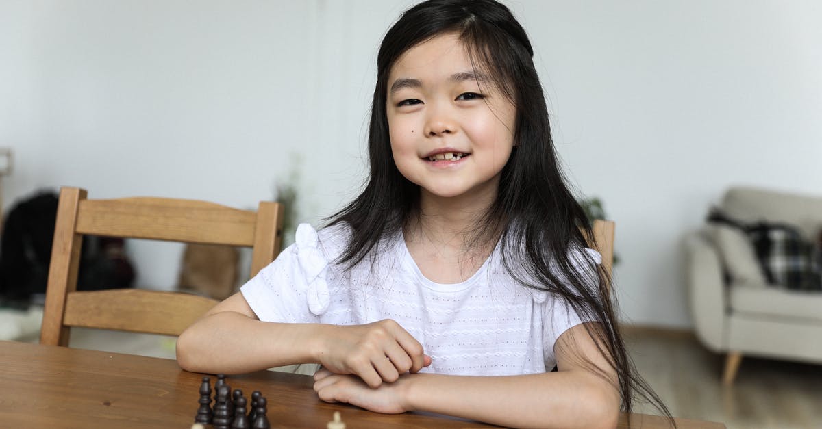 Will knowledge of Yiddish be useful traveling in Israel? - Happy cute Asian girl sitting at table with chessboard