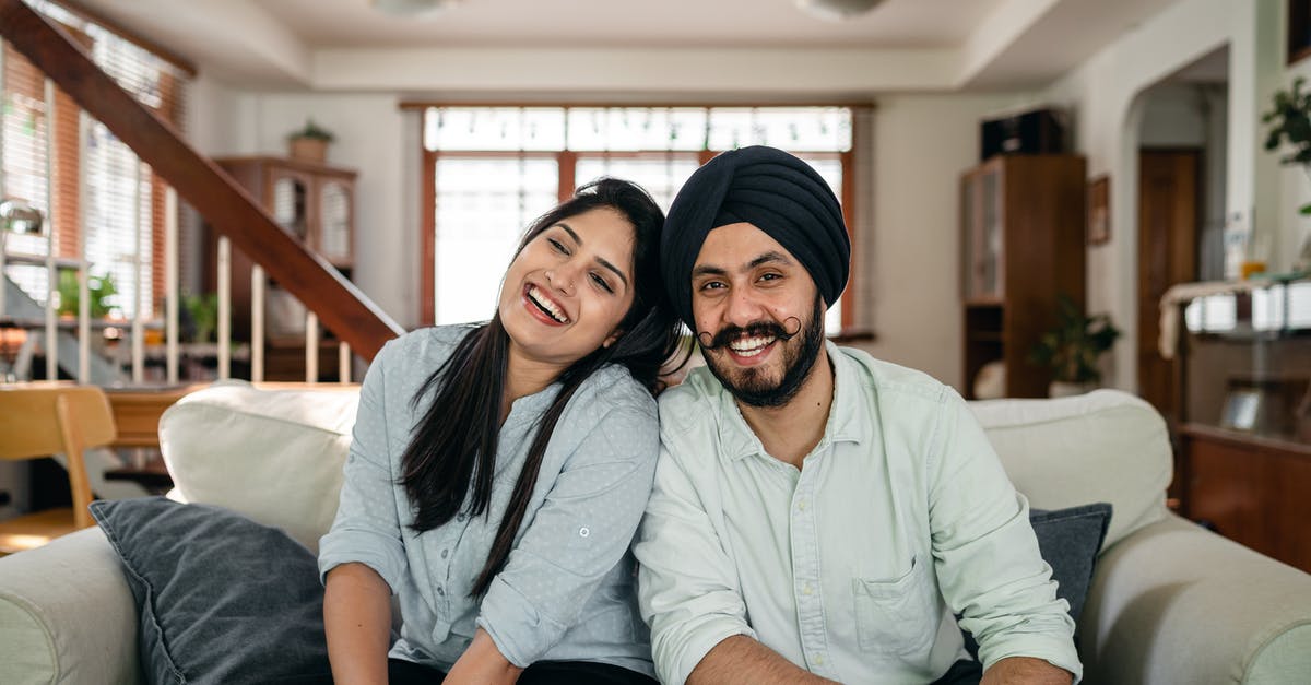 Will my boyfriend have any issues at UK border? [closed] - Delighted young Indian couple relaxing and laughing together on couch at home