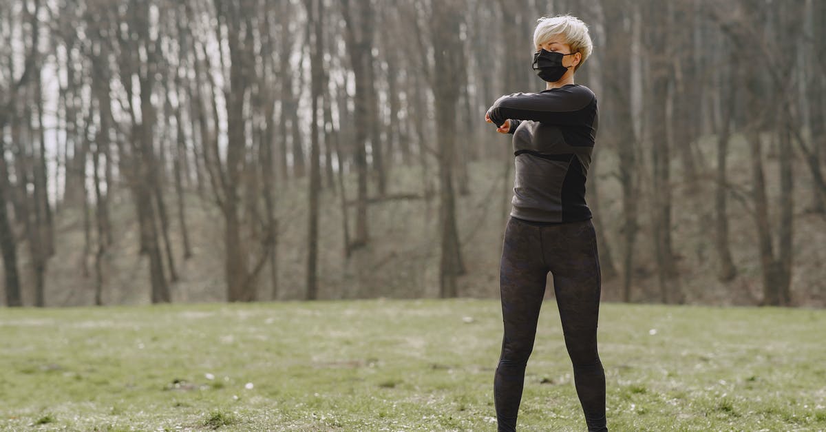 Will P&O demur if I turn up without a bicycle? - Full length young female in sportswear and mask making turns and kneading upper back while standing on green meadow in park