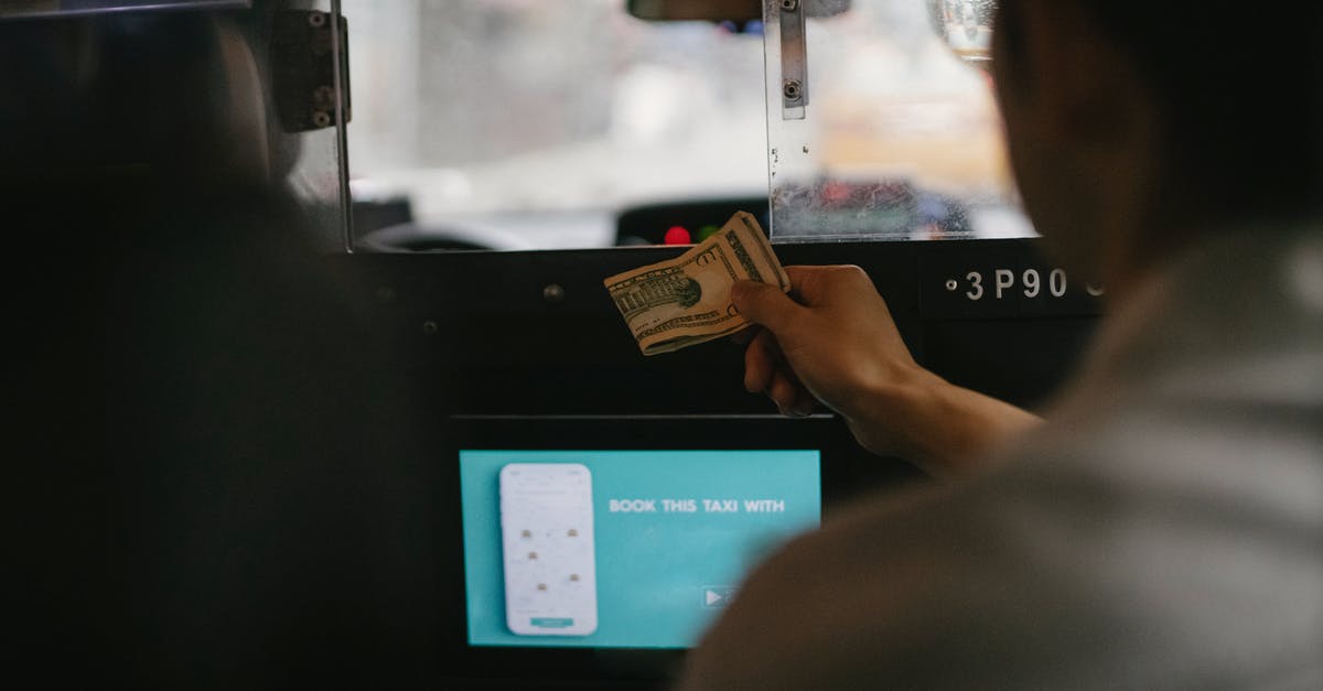 With car rental should I pay now or pay later? - Back view of taxi car interior with tablet screen located near passenger seat and client paying for ride