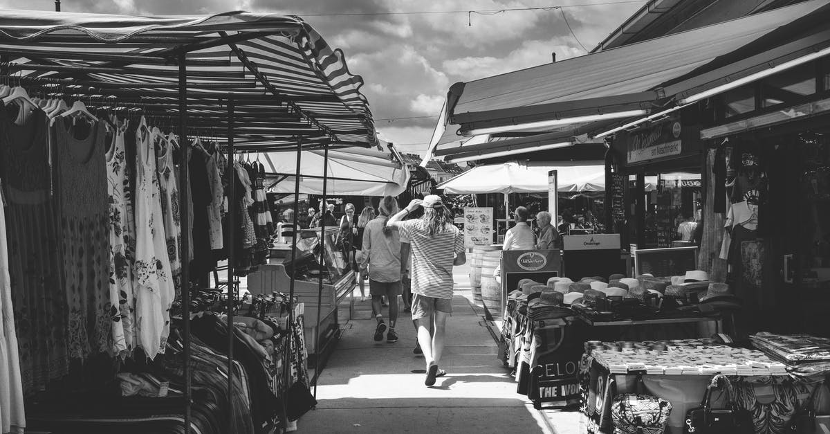 Wizz discount club - companions on different flight - Black and white of crowd of people strolling in market with different clothes and goods in daytime