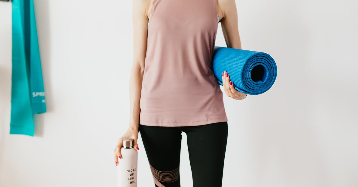 Wizz-air Discount Club companion travelling alone without the holder - Faceless slim female athlete in sportswear standing with blue fitness mat and water bottle while preparing for indoors workout