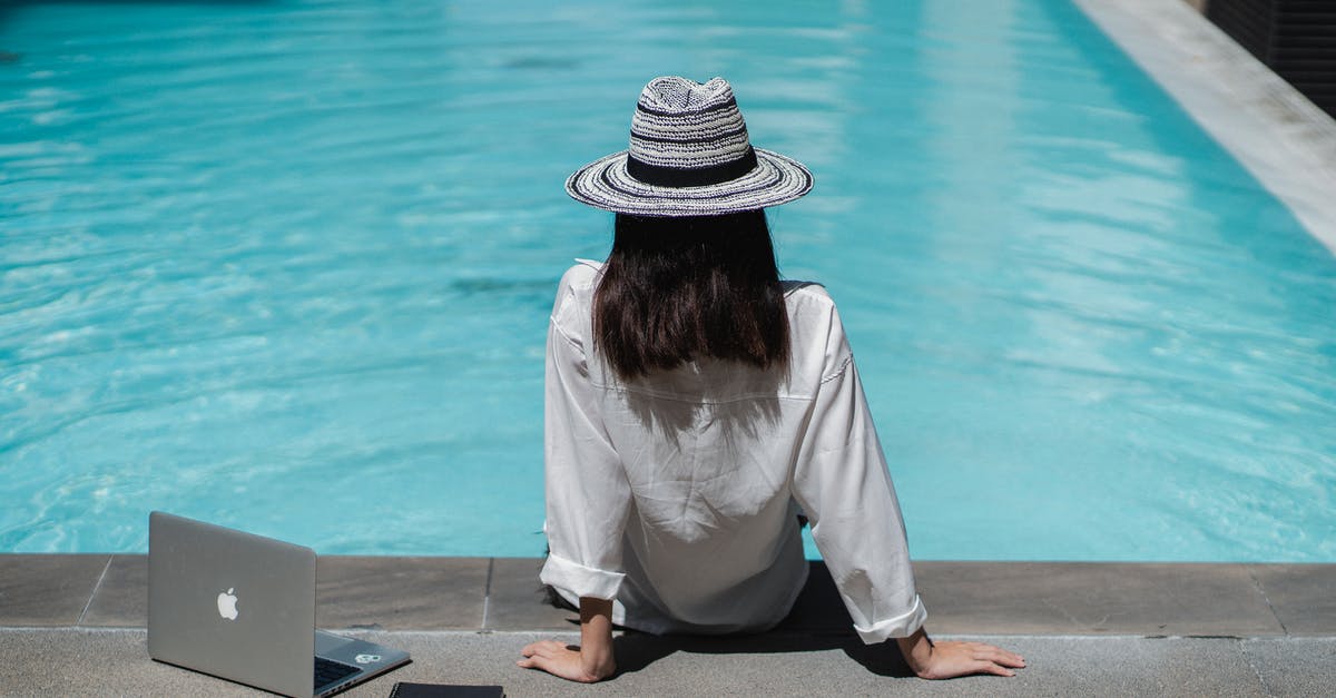 Working remotely on the French work and holiday visa? - Faceless female freelancer resting at poolside after work on laptop